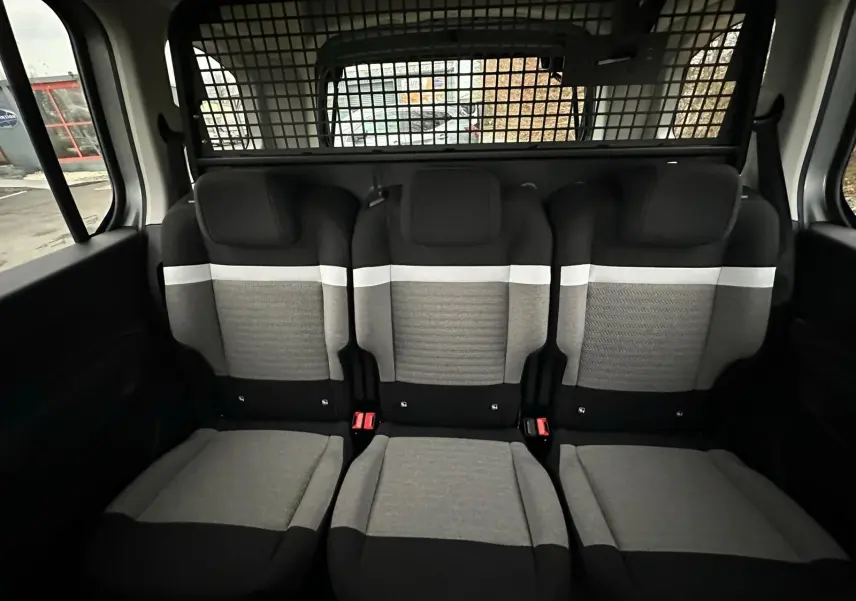 Vue intérieure arrière des sièges en tissu gris et noir du Citroën Berlingo N1 2025 avec séparation grillagée.