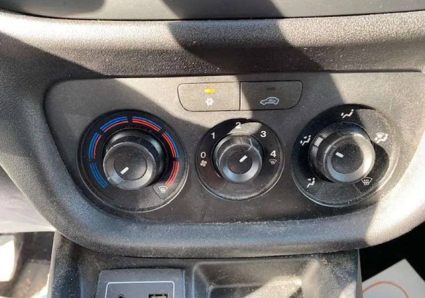 Détail du bouton de réglage de la climatisation avec indicateurs bleu et rouge dans un Fiat Doblo blanc de 2017.
