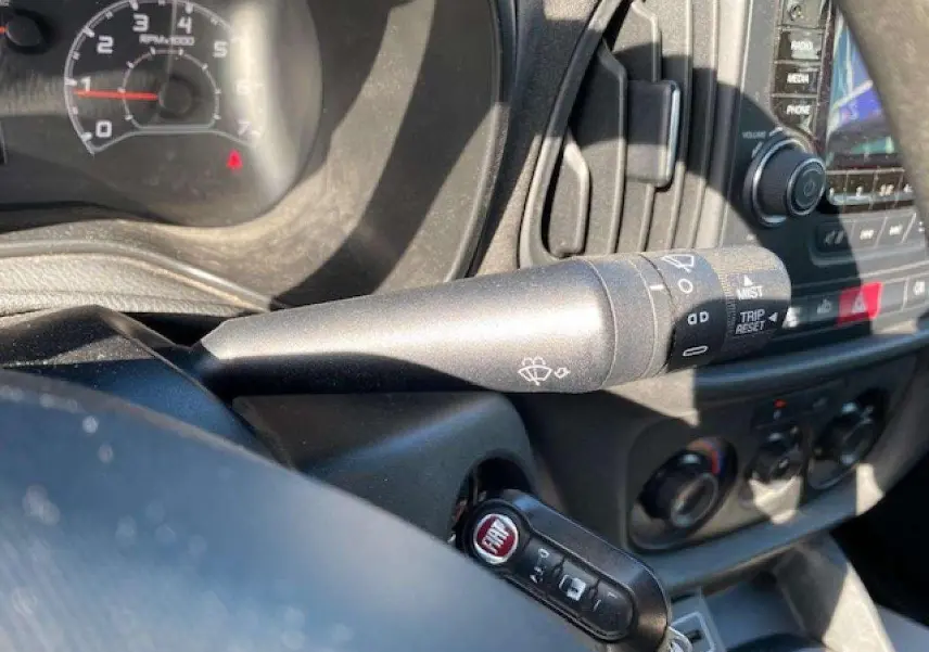 Gros plan sur la manette d'essuie-glace et la clé FIAT dans l'habitacle du Fiat Doblo blanc de 2017.