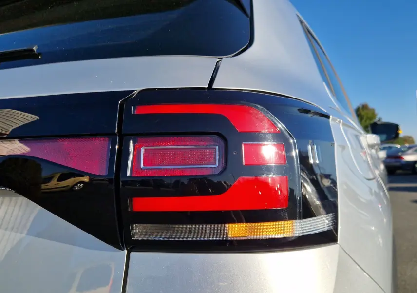 Gros plan sur le feu arrière droit rouge et noir d'un Volkswagen T-Cross argent métal 2019, sous un ciel bleu.