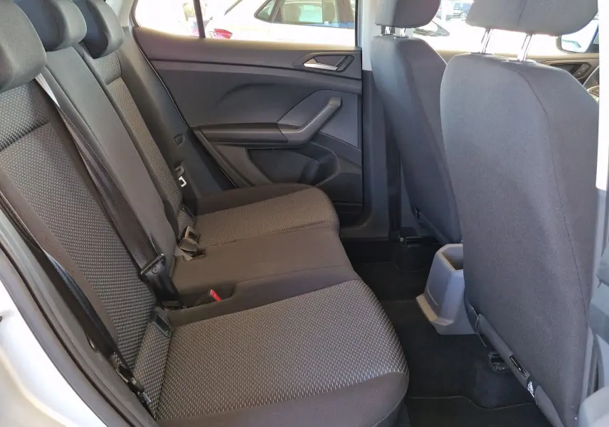 Vue intérieure arrière côté gauche du Volkswagen T-Cross argent métal 2019 avec sièges tissu gris et accoudoir central.