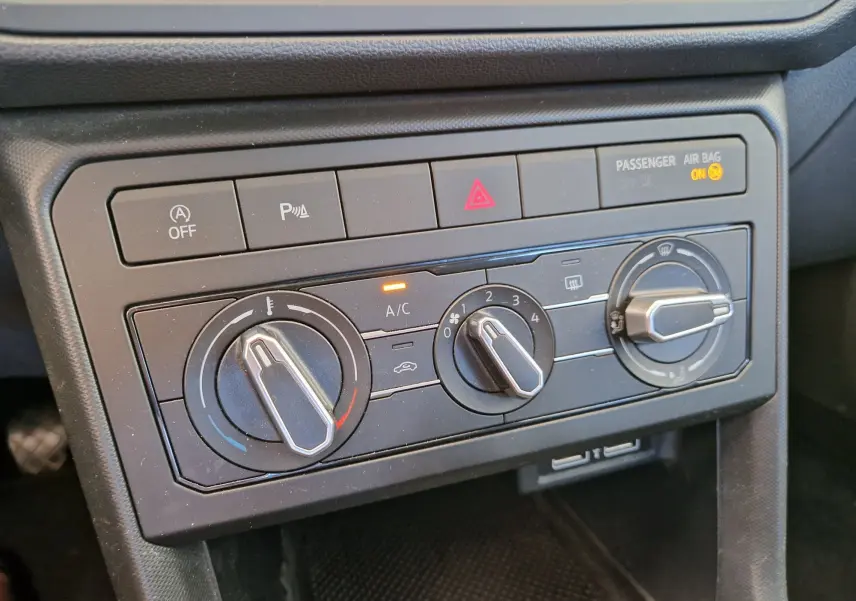 Panneau de commande de climatisation manuelle du Volkswagen T-Cross argent métal, avec réglages et voyants allumés.