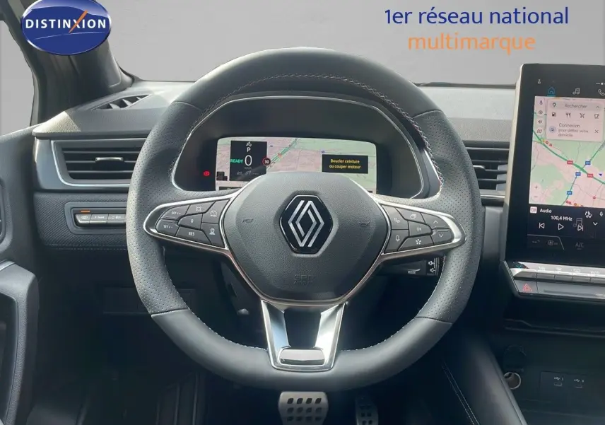 Vue centrée sur le volant en cuir perforé du Renault Captur E-Tech gris cassiopée, avec tableau de bord numérique et écran tactile.