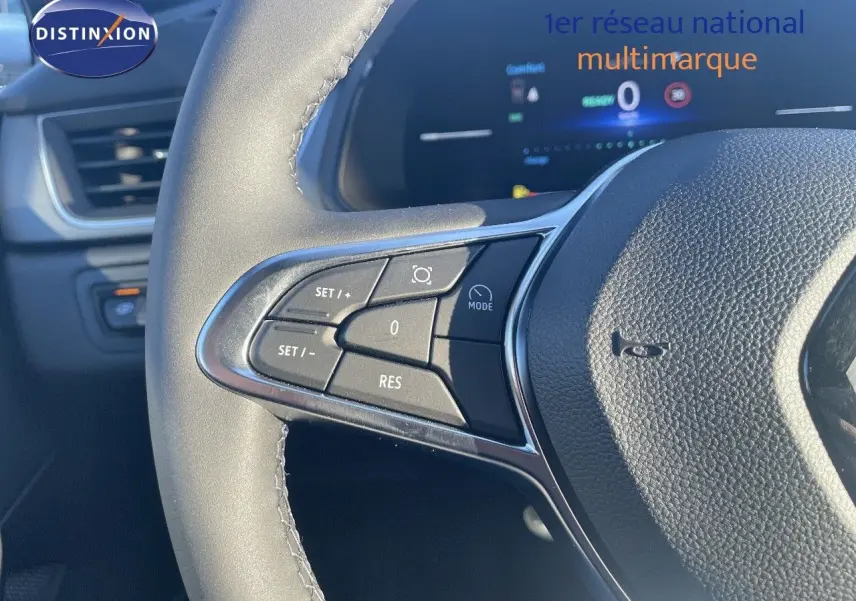 Gros plan sur le volant avec commandes intégrées du Renault Captur E-Tech hybride rouge passion toit noir, intérieur moderne.