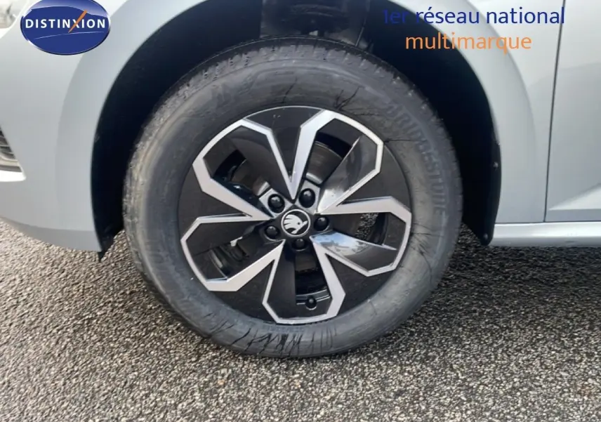 Gros plan sur la roue avant gauche du Skoda Kamiq gris argent métal avec jante alliage bicolore distinctive.