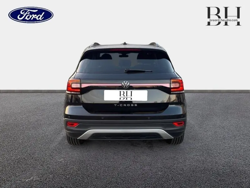 Vue arrière du Volkswagen T-Cross noir intense nacré, soulignant la ligne lumineuse et le logo central.