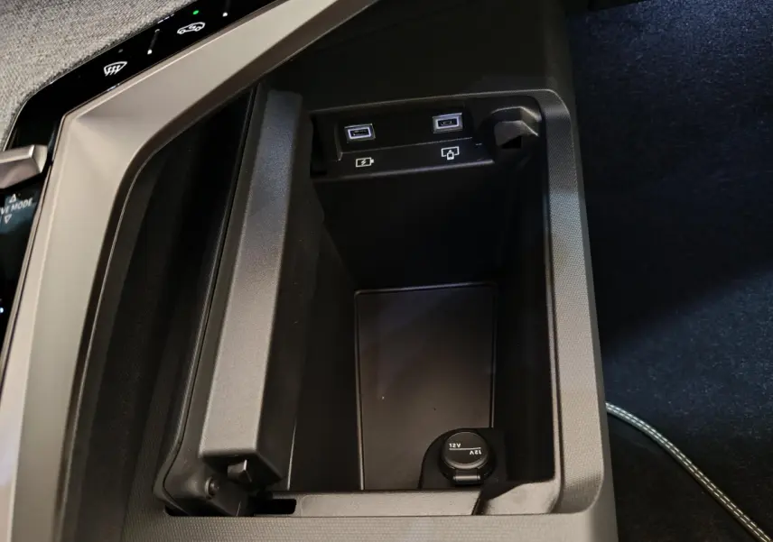 Vue rapprochée de la console centrale noire du Peugeot 3008 1.2 Hybrid 145 GT avec ports USB et prise 12V visibles.