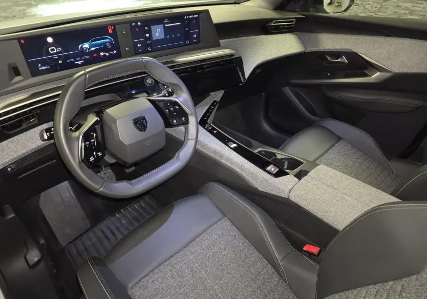 Vue intérieure côté conducteur du Peugeot 5008 2025, avec tableau de bord numérique et sellerie tissu gris et noir.