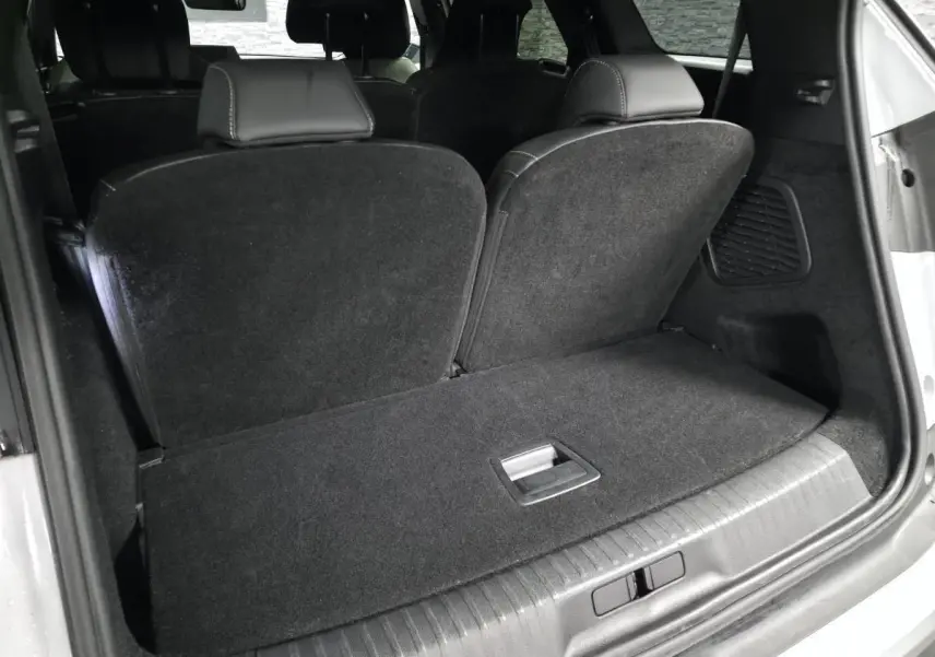 Coffre ouvert vu de l'arrière d'un Peugeot 5008 blanc, montrant la banquette rabattue et l'intérieur noir.