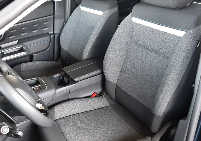 Vue intérieure côté avant gauche du Citroën C5 Aircross 2025, sièges tissu gris avec bande blanche décorative.