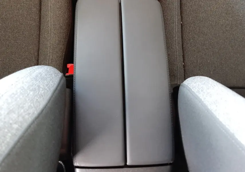 Vue plongeante sur l'accoudoir central gris et les sièges en tissu gris du Citroën C5 Aircross 2025.
