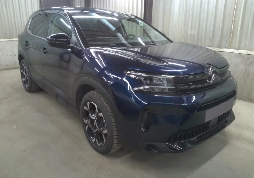 Vue 3/4 avant droite du Citroën C5 Aircross 2025 bleu éclipse avec calandre distinctive et jantes noires bicolores.