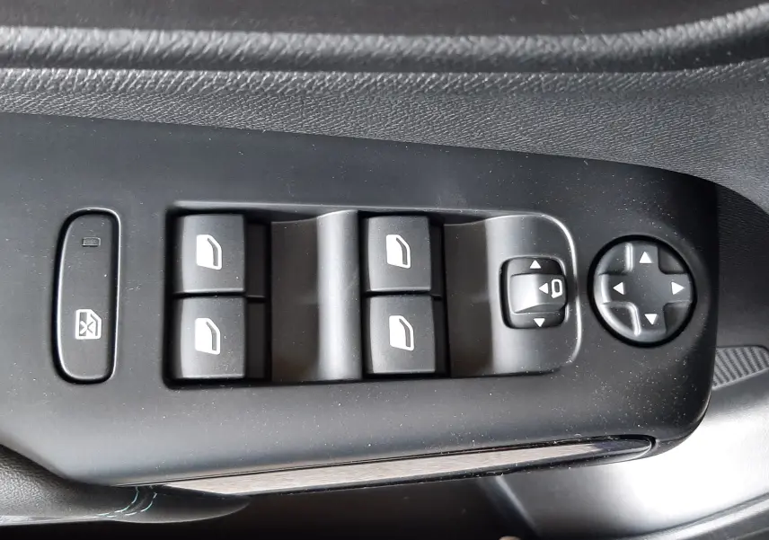 Gros plan sur les commandes de lève-vitres et réglage des rétroviseurs côté conducteur du Citroën C5 Aircross bleu Eclipse 2025.