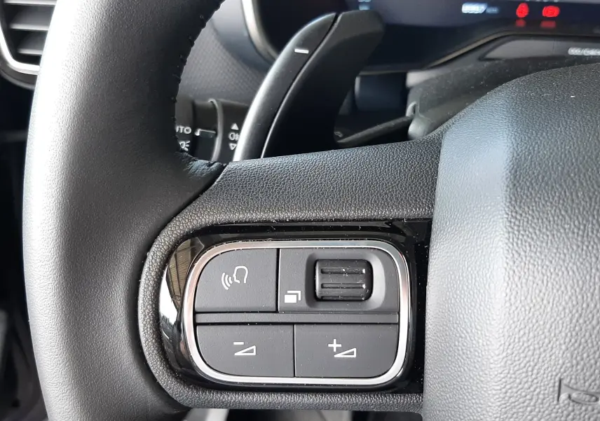 Gros plan sur les commandes au volant côté gauche du Citroën C5 Aircross bleu Eclipse, avec boutons de volume et commande vocale.