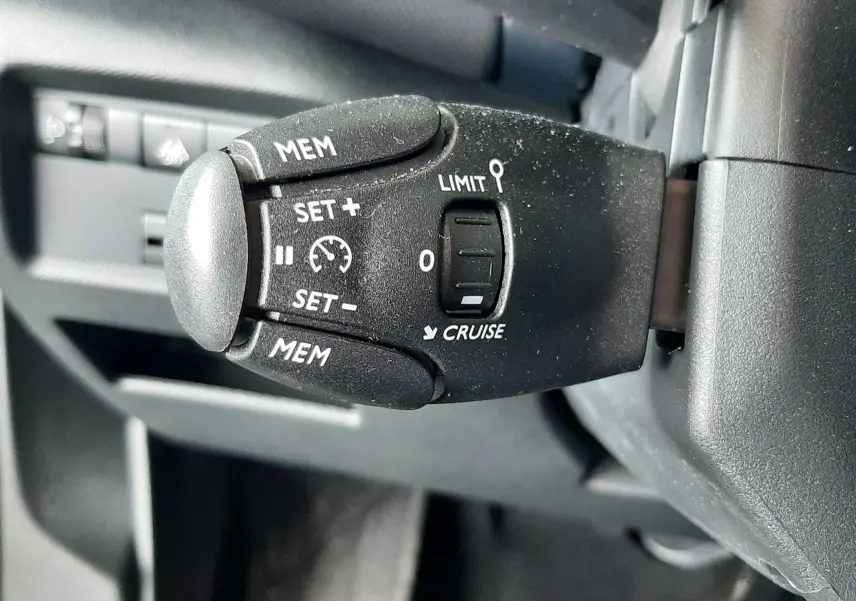 Gros plan sur la commande de régulateur de vitesse noire dans l'habitacle d'une Citroën C5 Aircross 2025.
