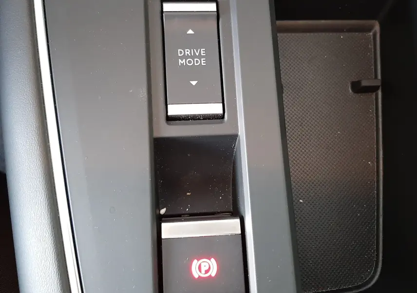 Vue rapprochée du bouton de mode de conduite et frein à main électronique sur la console centrale noire du Citroën C5 Aircross.