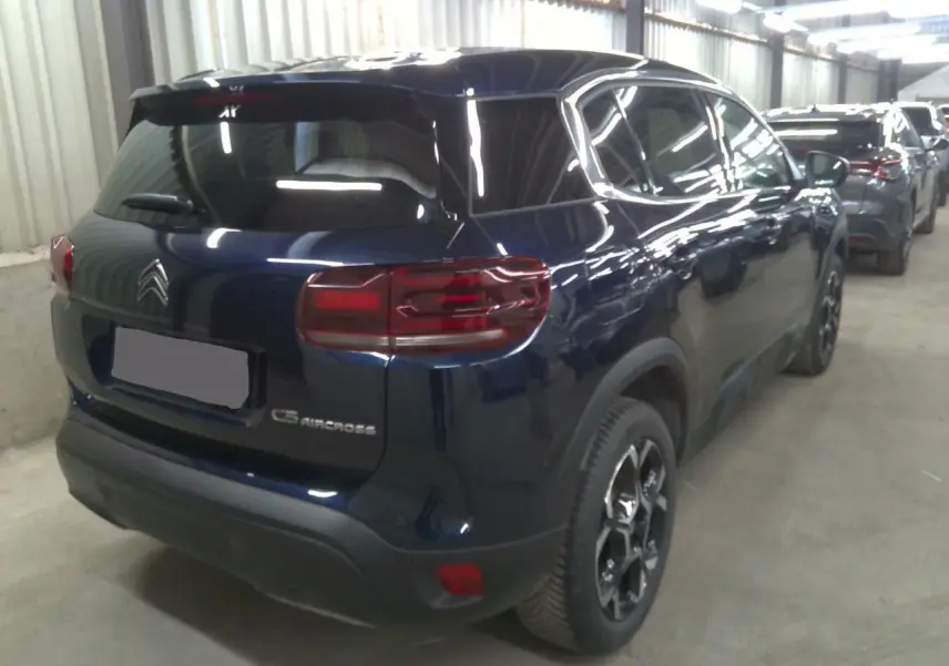 Vue 3/4 arrière droite du Citroën C5 Aircross bleu éclipse avec feux arrière allongés et jantes noires distinctives.