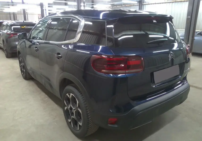 Vue 3/4 arrière droite du Citroën C5 Aircross 2025 bleu éclipse avec feux arrière distinctifs et jantes stylisées.