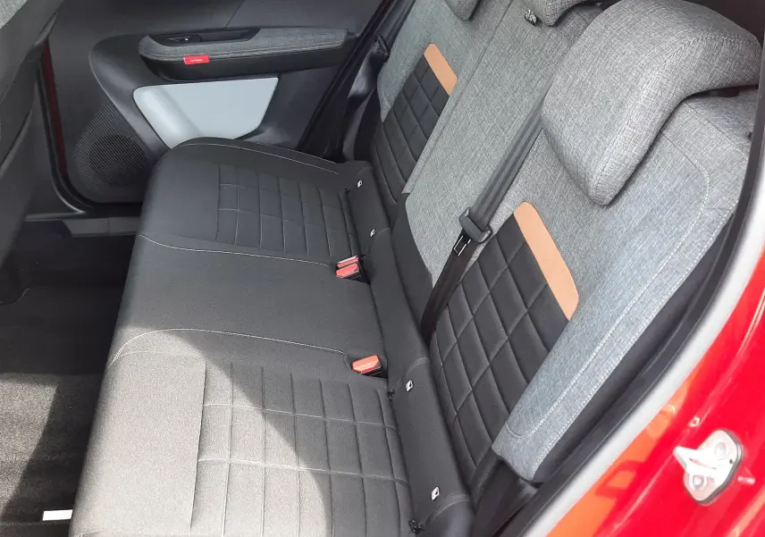 Vue intérieure côté arrière droit du Citroën C3 Aircross rouge Elixir, sièges arrière gris et noir avec inserts marron.