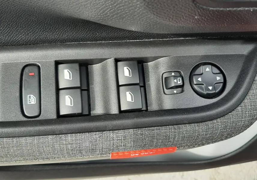 Gros plan sur les commandes de lève-vitres et réglage des rétroviseurs côté conducteur du Citroën C3 Aircross 2025.