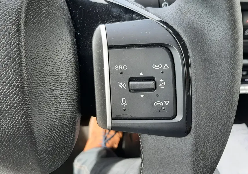 Gros plan sur les commandes au volant côté gauche du Citroën C3 Aircross rouge Elixir, avec boutons de volume et appel.