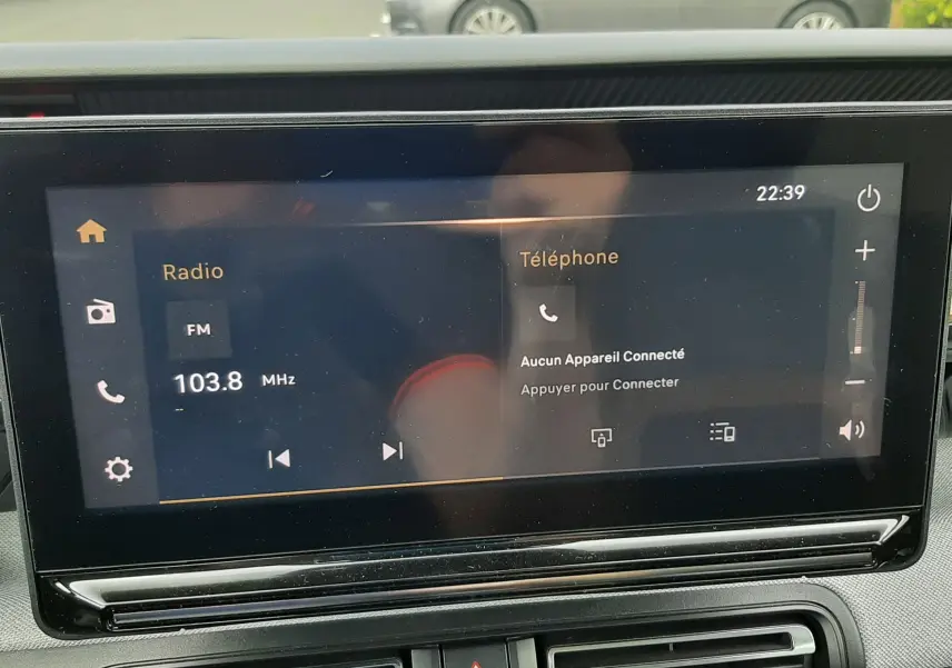 Écran tactile central de la Citroën C3 Aircross rouge Elixir, affichant la radio FM et la connexion téléphone, vue intérieure frontale.