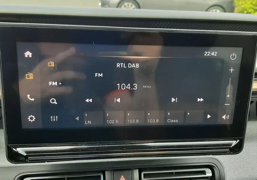Écran tactile central de la Citroën C3 Aircross 2025 affichant la radio FM à 104.3 MHz, avec commandes et aérateurs en dessous.