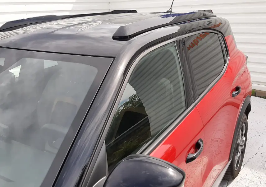 Vue de côté droit avant d'une Citroën C3 Aircross rouge Elixir avec toit noir brillant et rétroviseur noir.
