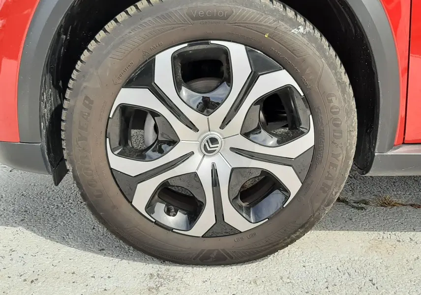 Gros plan sur la roue avant gauche d'une Citroën C3 Aircross rouge Elixir avec jante alliage bicolore et pneu Goodyear.
