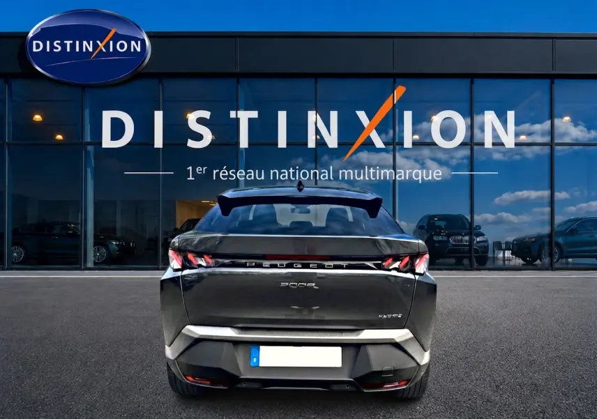 Vue arrière d’un Peugeot 3008 gris titane 2025 avec feux LED et becquet arrière, devant une vitrine Distinxion.