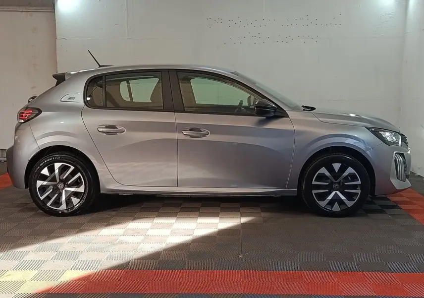 Peugeot 208 électrique gris clair vue de profil côté gauche, avec jantes stylisées et feux arrière LED.