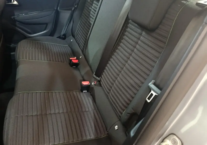 Vue latérale des sièges arrière noirs avec surpiqûres vertes d'une Peugeot 208 électrique gris clair 2024.