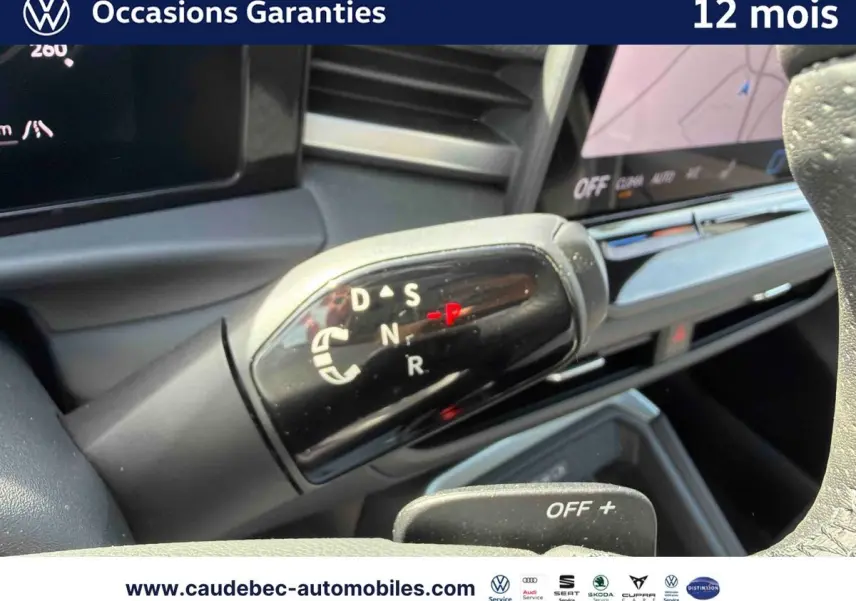Gros plan sur le levier de vitesses DSG7 noir brillant du Volkswagen T-Roc blanc, avec tableau de bord en arrière-plan.