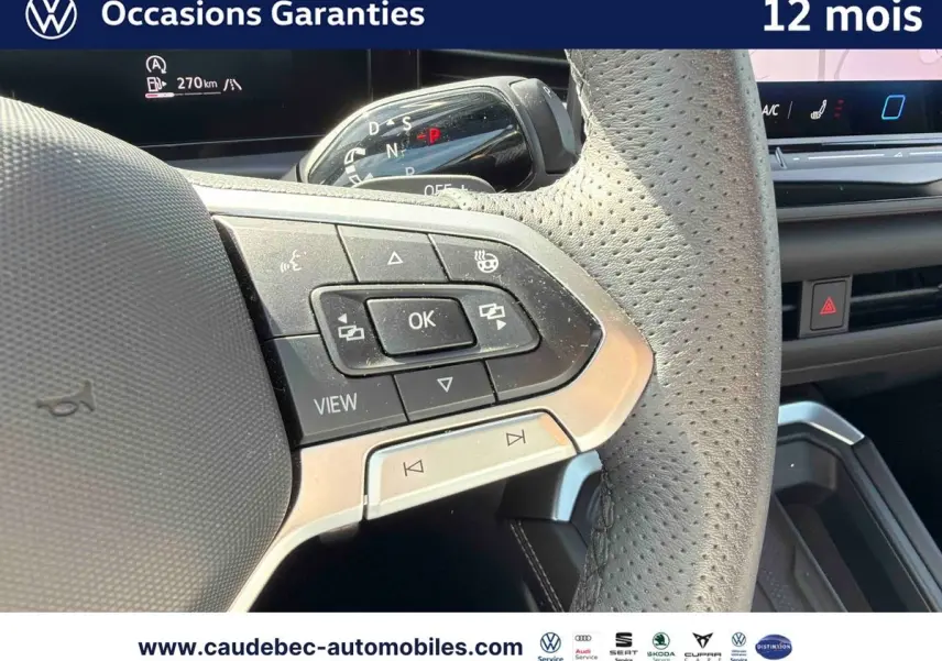 Gros plan sur le volant cuir perforé du Volkswagen T-Roc 2025 avec commandes multifonctions et palettes au volant.