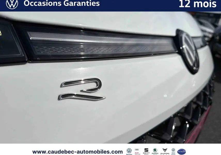 Gros plan sur la calandre avant blanche du Volkswagen T-Roc avec logo VW et badge R lumineux.
