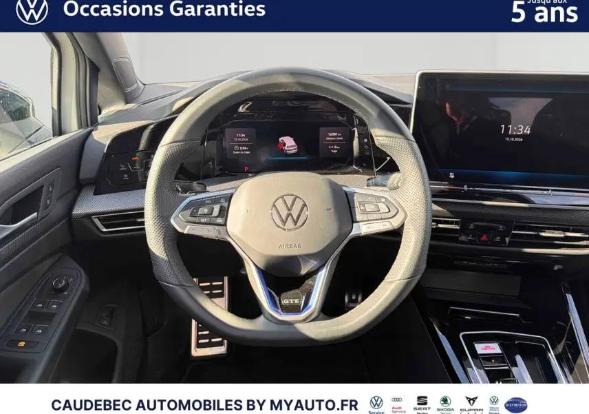 Vue intérieure centrée sur le volant sport multifonction GTE et le tableau de bord digital de la Volkswagen Golf 1.5 eHybrid blanche.