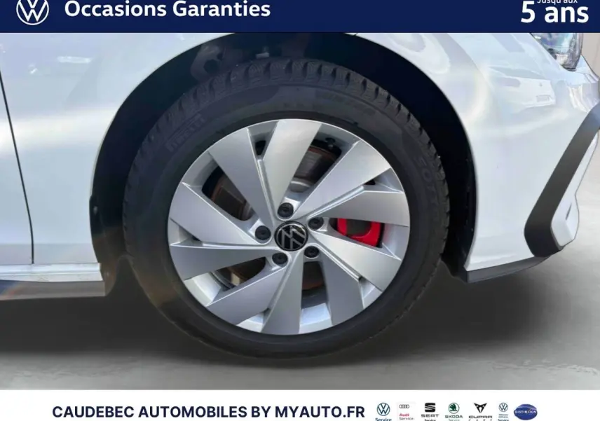 Gros plan sur la roue avant gauche d'une Volkswagen Golf blanche avec étrier de frein rouge visible.