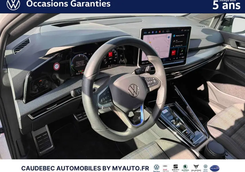 Intérieur de Volkswagen Golf 1.5 eHybrid 2026 vu côté conducteur, avec volant cuir et écran tactile central.
