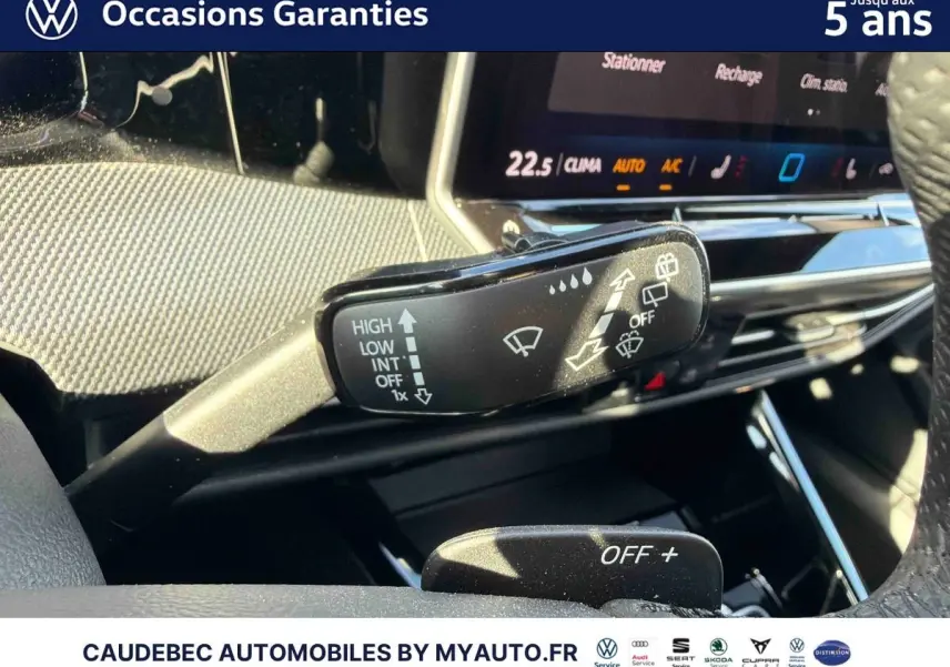 Gros plan sur la commande d’essuie-glace à gauche du volant dans l’habitacle lumineux d’une Volkswagen Golf blanche.