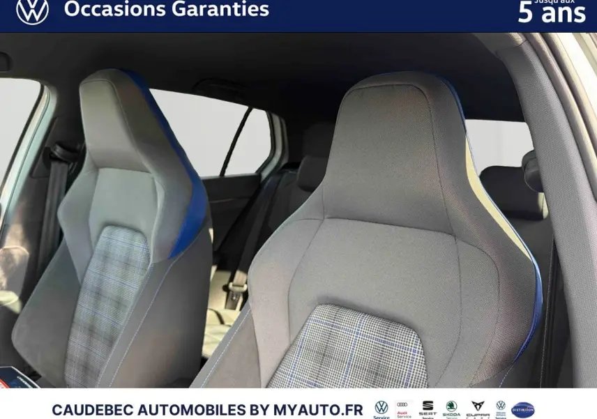 Gros plan sur les sièges avant sport gris avec surpiqûres bleues et tissu à carreaux de la Volkswagen Golf 1.5 eHybrid blanche.