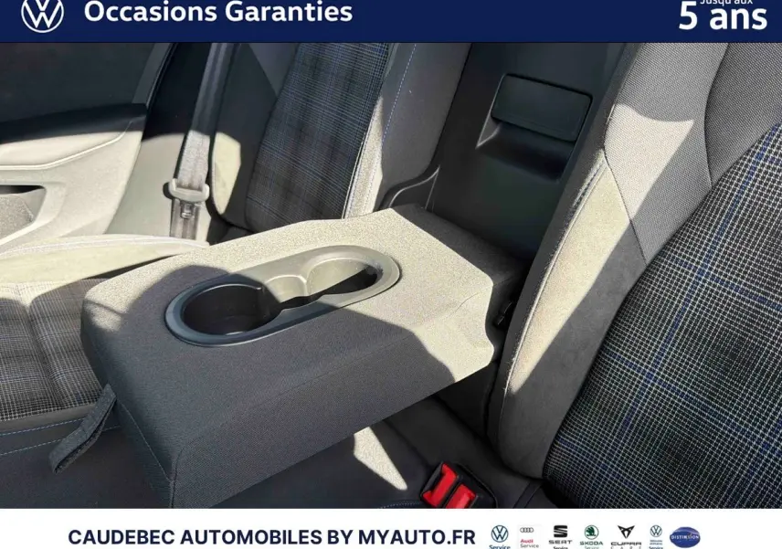 Gros plan sur l'accoudoir central arrière avec porte-gobelets, sièges tissu à motif écossais bleu et gris.