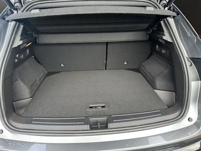 Coffre ouvert vu de l'arrière d'un Renault Austral PH2 Techno bi-ton gris schiste et toit noir, intérieur spacieux et tapis gris.