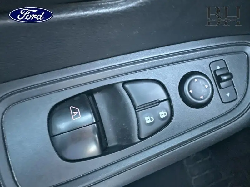 Gros plan sur les commandes de lève-vitres et réglages des rétroviseurs côté conducteur d'une Nissan Micra gris acier.