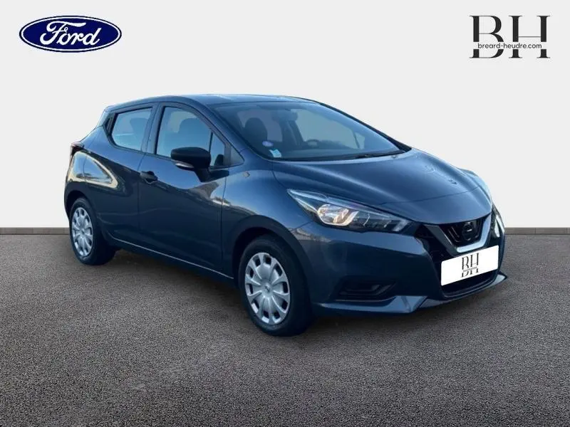 Vue 3/4 avant droite d'une Nissan Micra gris acier 2018 avec jantes acier et feux halogènes allumés.