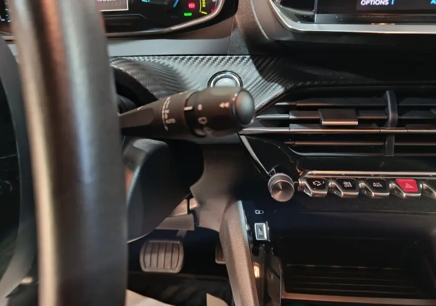 Vue intérieure rapprochée du tableau de bord et volant cuir noir du Peugeot 208 électrique Active Business 2020.