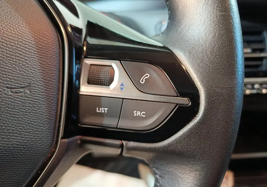 Gros plan sur le volant cuir noir de la Peugeot 208 électrique Active Business, avec commandes multifonctions visibles.