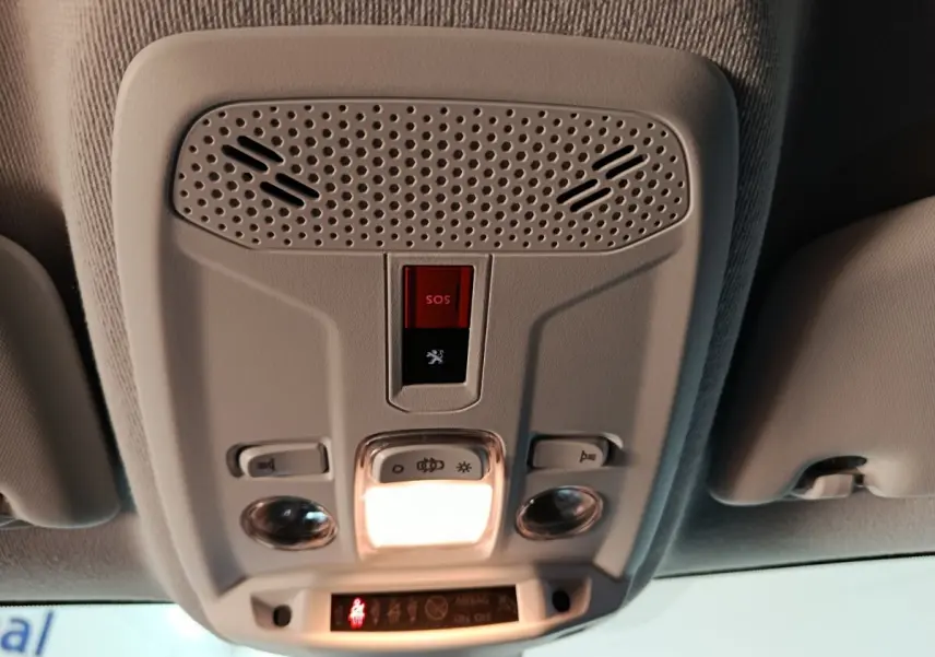 Vue en contre-plongée du plafonnier intérieur gris clair du Peugeot 208 Electrique Active Business avec bouton SOS rouge allumé.