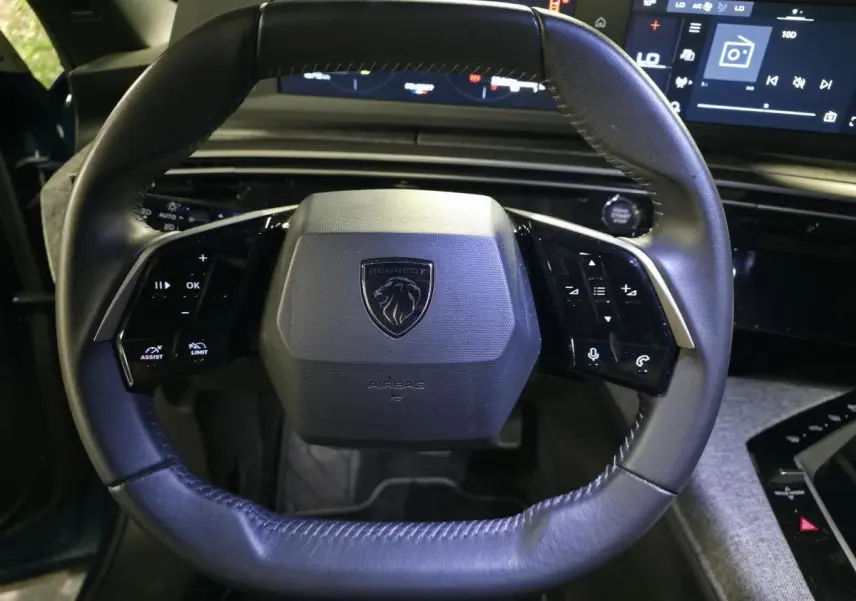 Gros plan sur le volant noir en cuir du Peugeot 5008 2025 avec commandes intégrées et logo central lion.