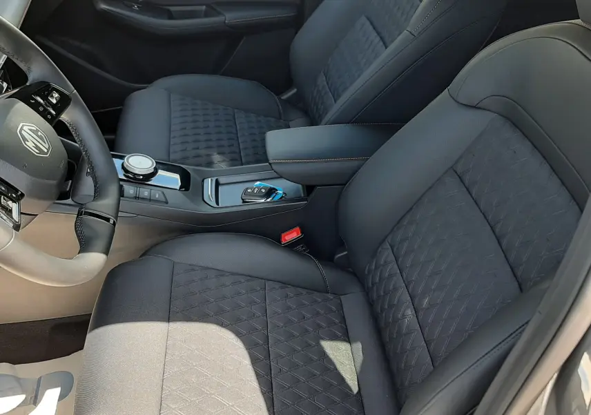 Vue intérieure côté conducteur du MG3 1.5L HYBRID+ 195CH Luxury avec sièges noirs en tissu et cuir, console centrale moderne.