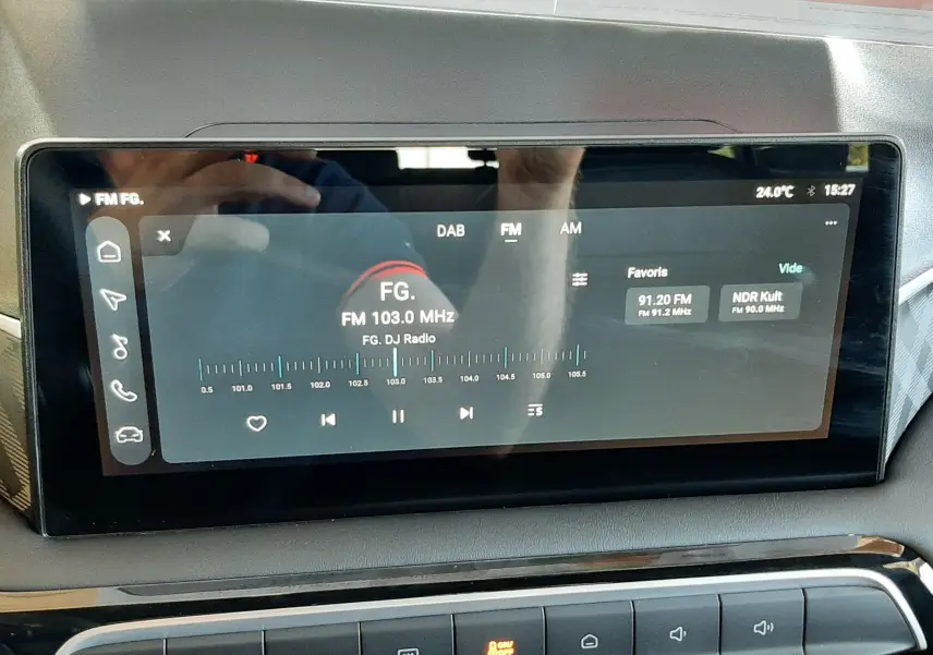 Écran tactile central de la MG3 2026 affichant la radio FM sur fond noir, avec commandes climatisation en dessous.